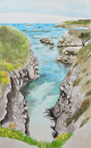 Cove with bright blue water framed by rocky cliffs with grasses growing from them