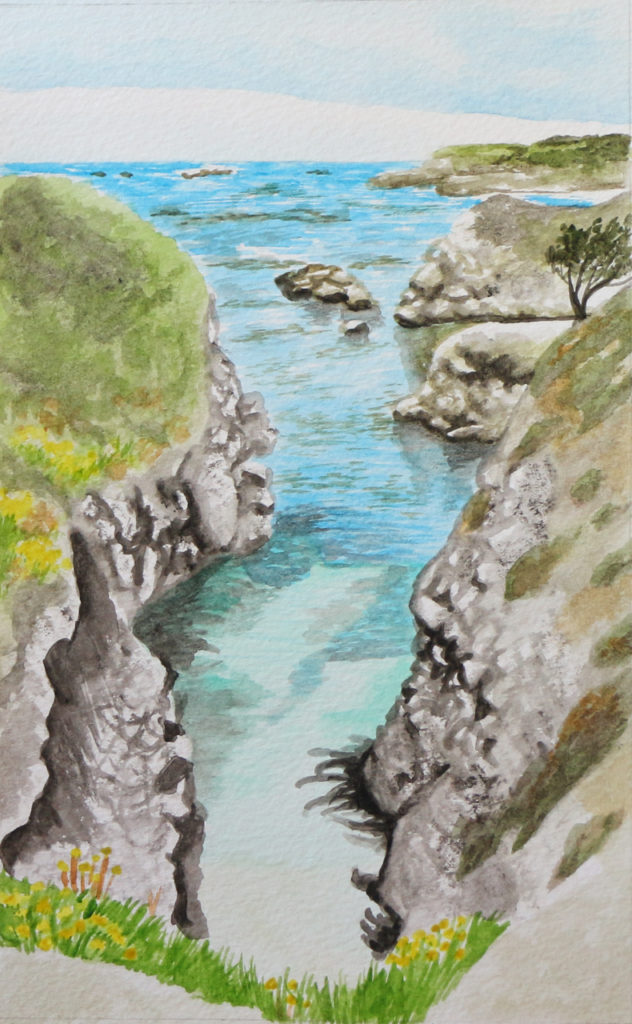 Cove with bright blue water framed by rocky cliffs with grasses growing from them